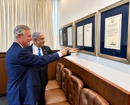 Political leaders review framed diplomatic documents in a government office.