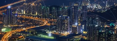 Skyline at night with illuminated bridges and buildings, illustrating global trade and business risk.